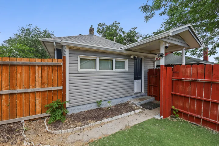 Rear exterior with light gray horizontal siding, an asphalt shingle roof, and a covered entry