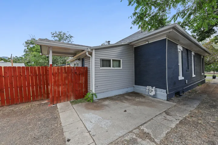 Exterior featuring a red wood fence, gray siding, and dark-painted brick