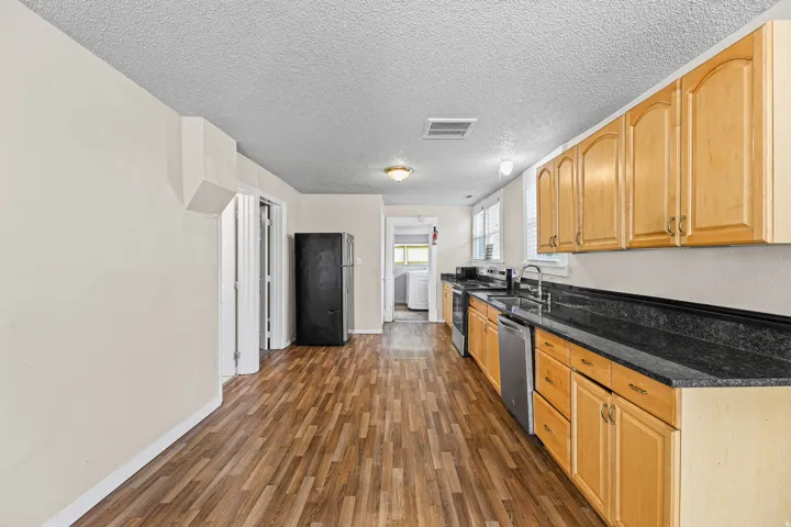 Kitchen featuring wood-finish flooring, light wood cabinetry, dark countertops, and stainless steel appliances