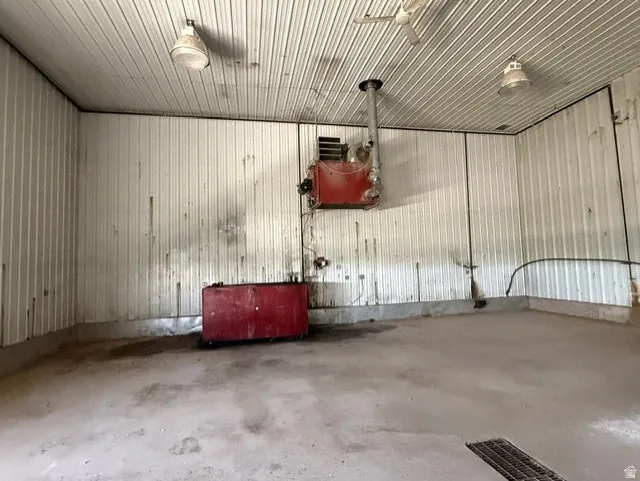 Utility space featuring a concrete floor with drainage, corrugated metal walls, and a corrugated metal ceiling