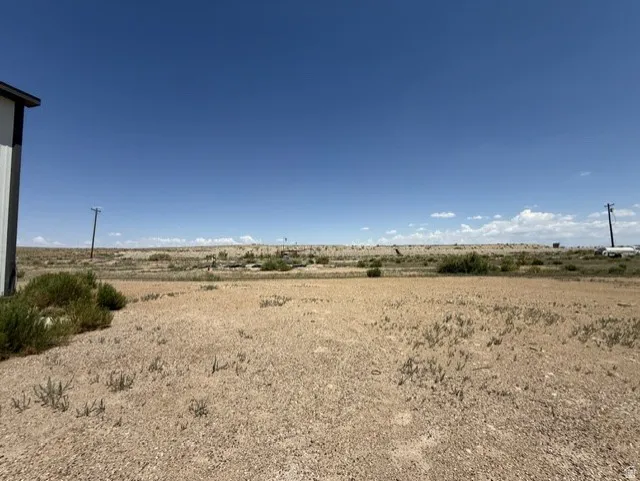 Expansive open land with a clear blue sky, featuring a distant natural landscape
