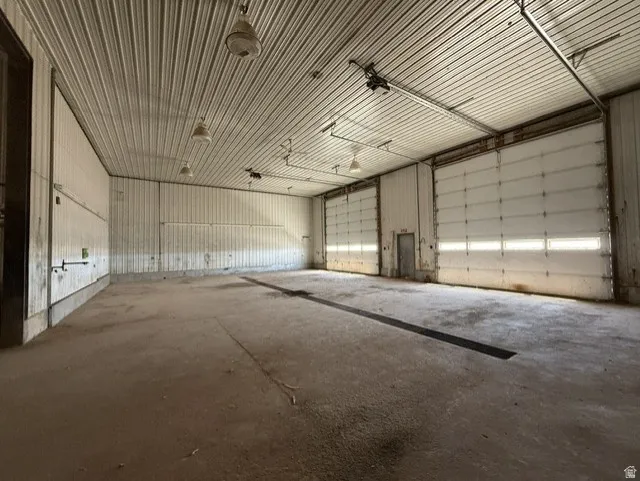 Spacious interior with concrete flooring and corrugated metal walls. Two 16x16' electric roll up doors.