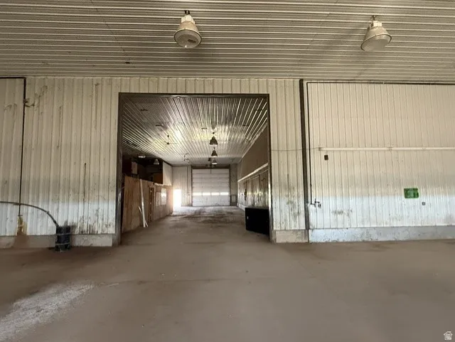 Spacious commercial interior featuring a concrete floor, corrugated metal walls, and a matching corrugated metal ceiling