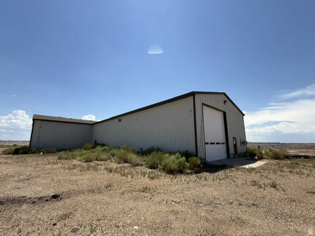 Industrial-style building featuring a large white roll-up door, corrugated metal siding, and a dark-trimmed gable roof