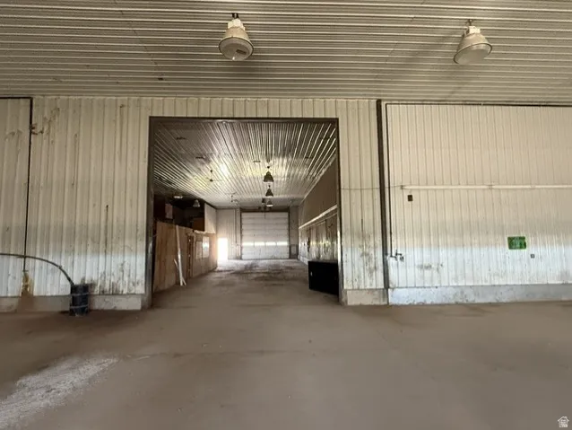 Spacious commercial interior featuring a concrete floor, corrugated metal walls, and a matching corrugated metal ceiling
