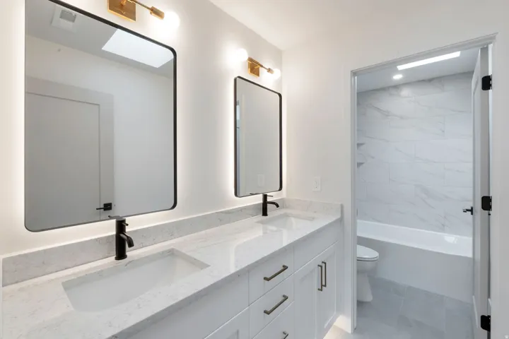 Dual vanity featuring integrated sinks, light-toned countertops, and matte black faucets