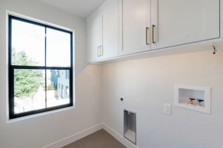 Utility area featuring shaker-style cabinetry with gold-toned hardware, under-cabinet lighting, and a large black-framed window