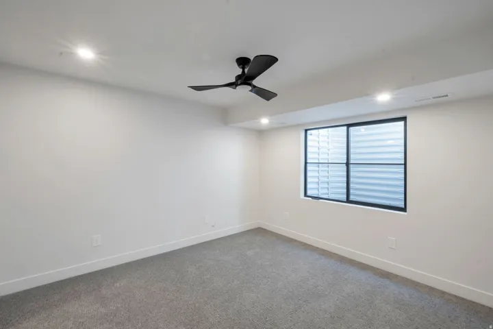 Spacious room featuring a large egress window, recessed lighting, and a contemporary ceiling fan