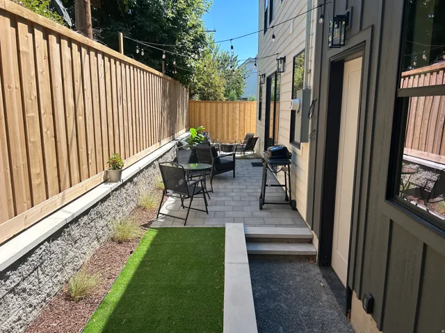 Paved patio area featuring composite fencing and an artificial turf section