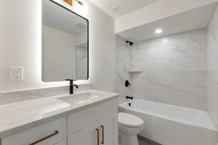 Modern bathroom featuring a single vanity with a quartz countertop, integrated sink, and matte black faucet