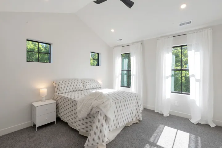 Vaulted ceiling room featuring multiple black-framed windows, recessed lighting, and a ceiling fan