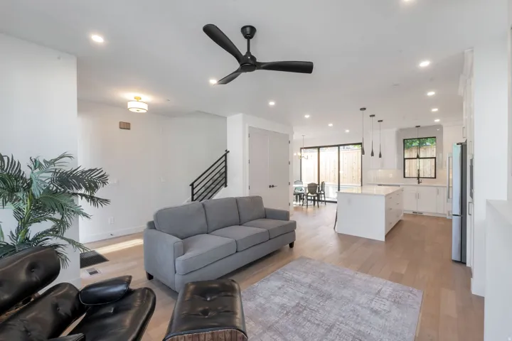 Open-concept living area featuring light wood-finish flooring, recessed lighting, and a modern ceiling fan