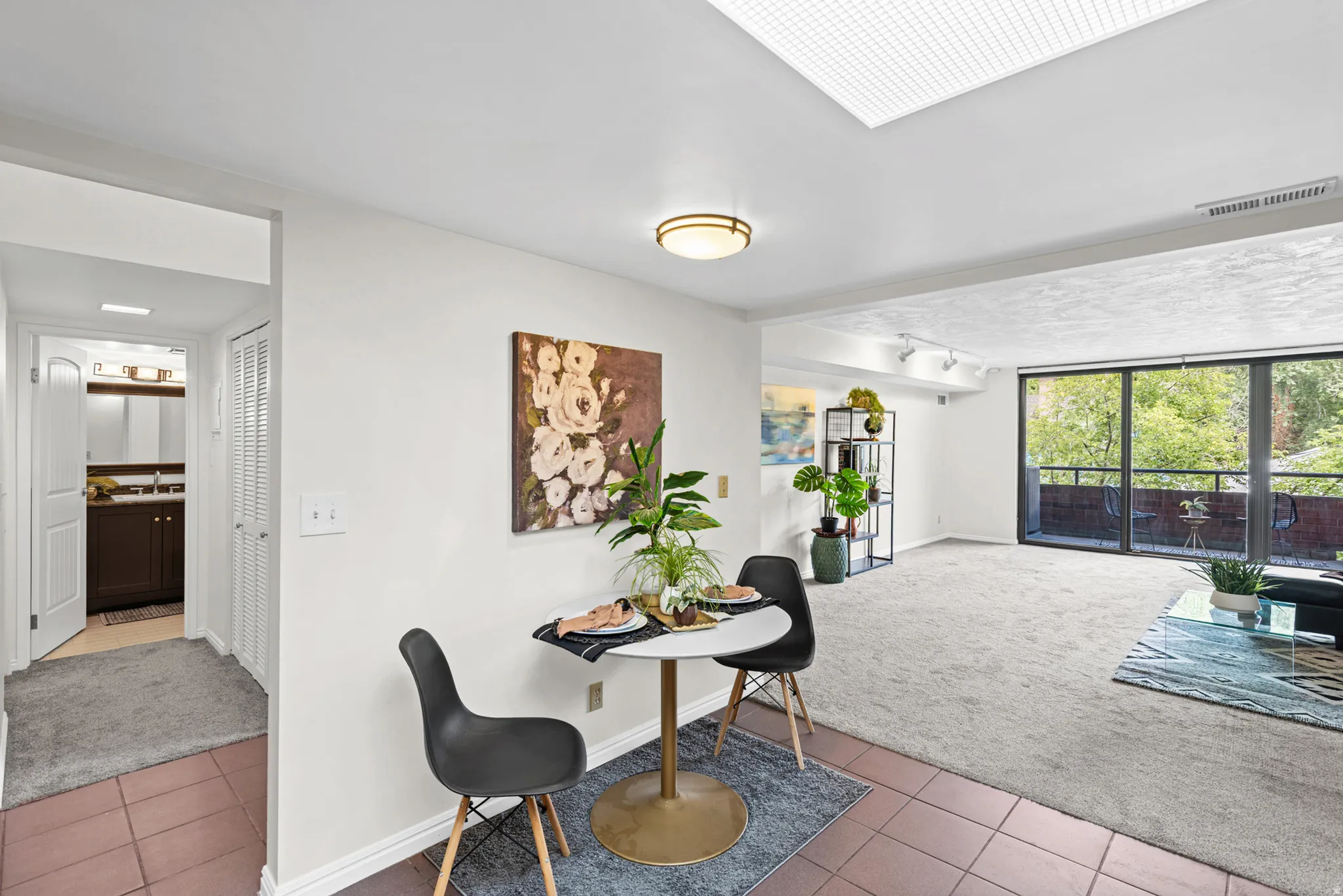 Living area featuring a large glass slider to an exterior balcony, light-colored carpeting, and track lighting