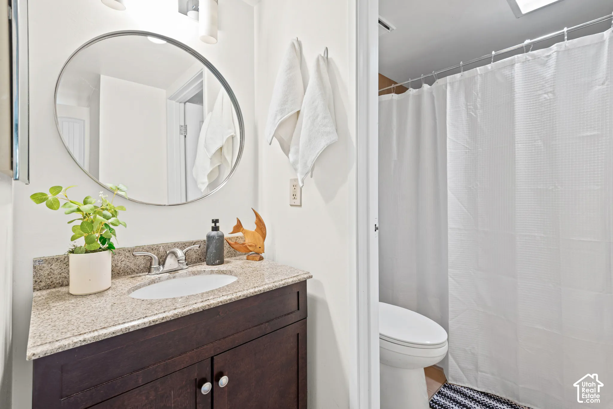 Bathroom featuring a dark wood-finish vanity with a granite countertop, undermount sink, and chrome faucet