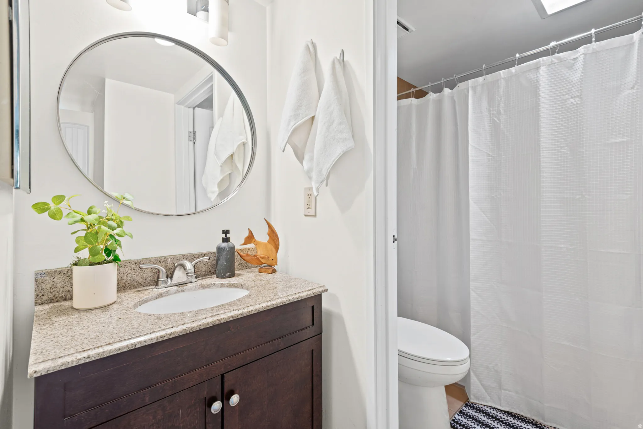 Bathroom featuring a dark wood-finish vanity with a granite countertop, undermount sink, and chrome faucet