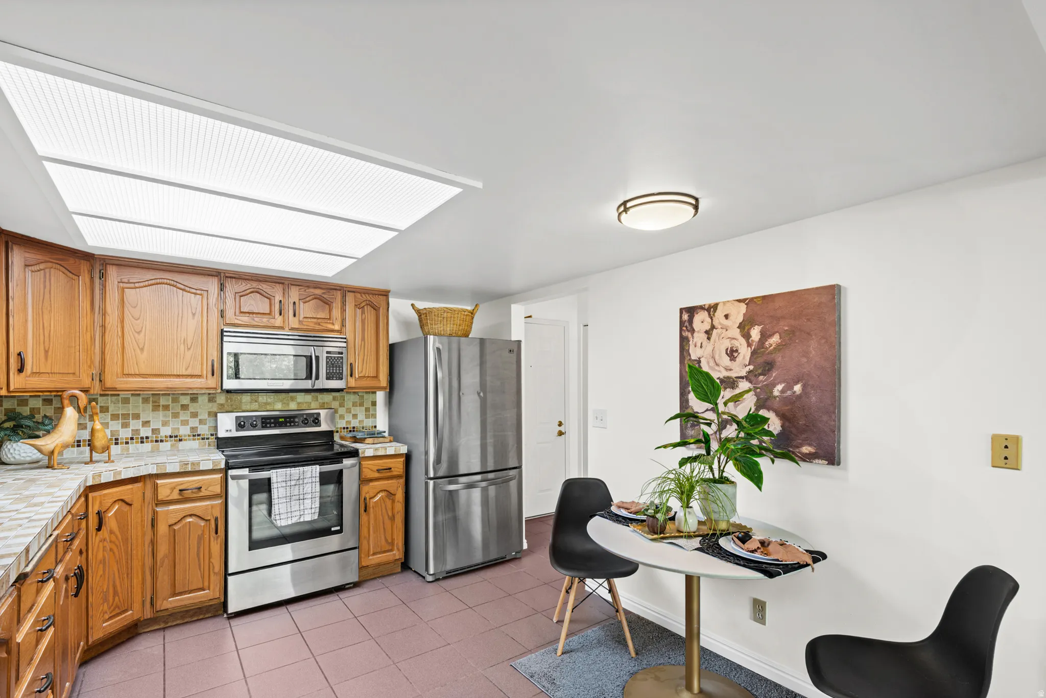 Kitchen featuring wood cabinetry, stainless steel appliances, and a skylight