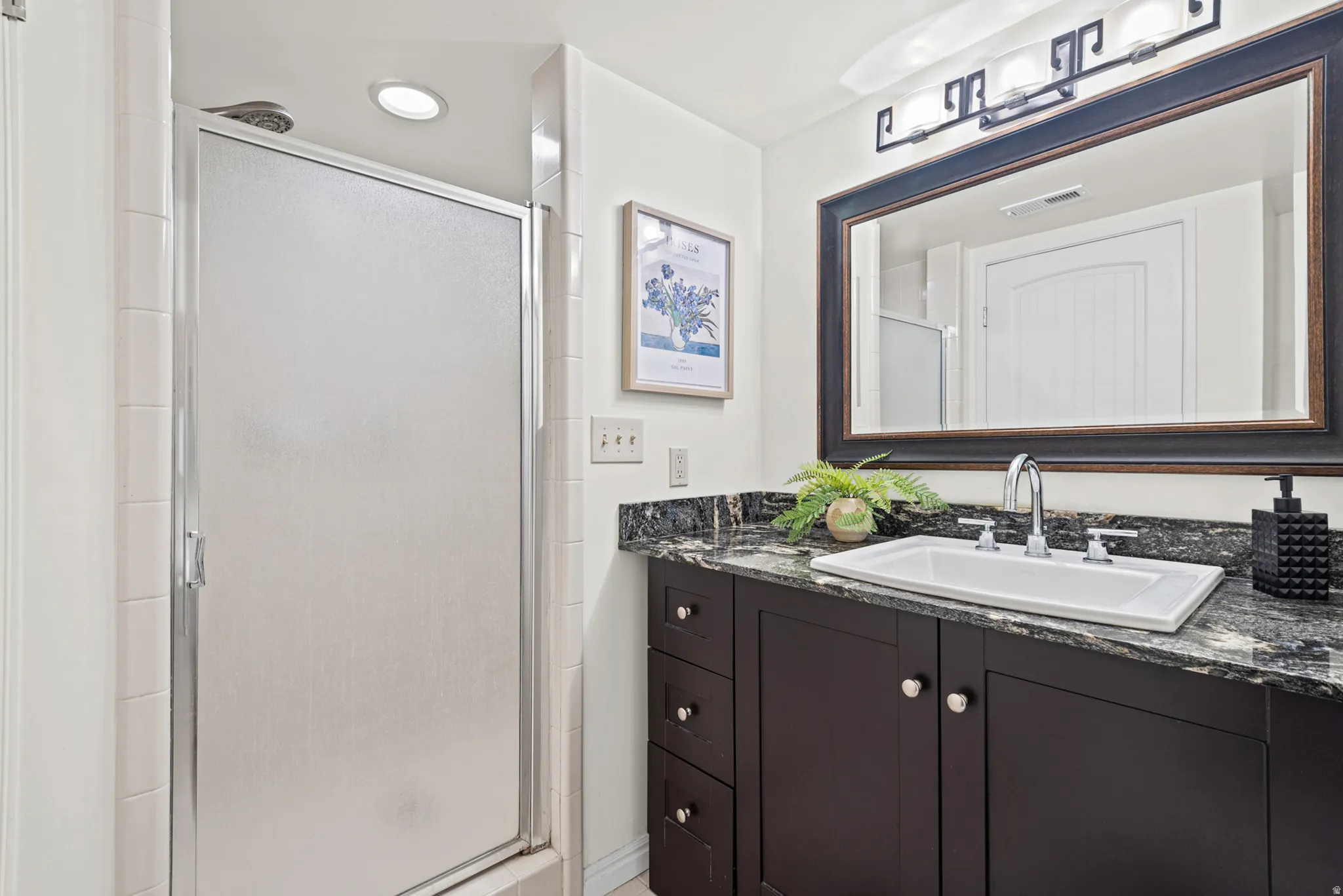 Bathroom featuring a dark wood-finish vanity with a granite countertop, undermount sink, and chrome fixtures