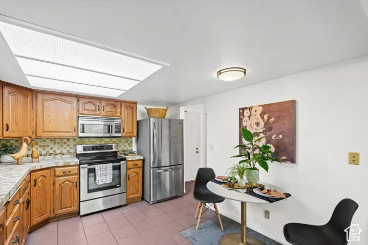 Kitchen featuring wood cabinetry, stainless steel appliances, and a skylight