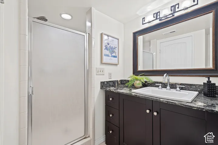 Bathroom featuring a dark wood-finish vanity with a granite countertop, undermount sink, and chrome fixtures