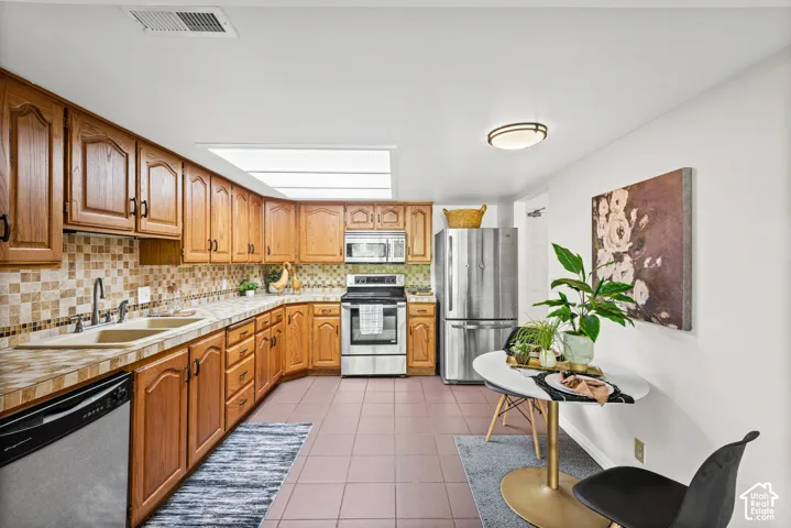 Kitchen with wood cabinetry, stainless steel appliances, and a tiled backsplash