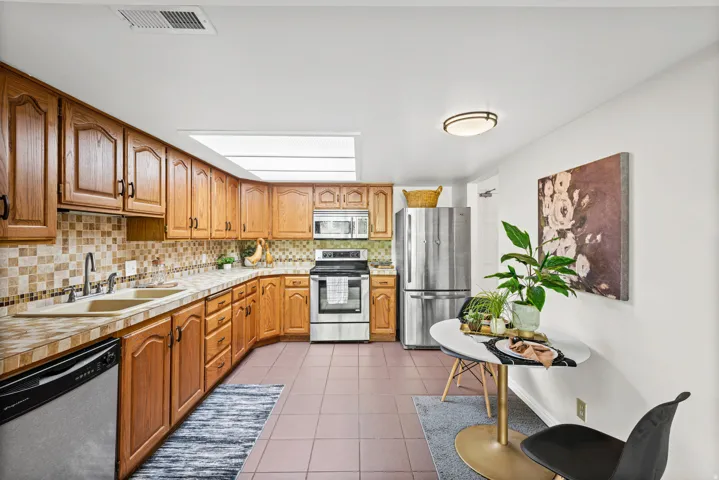 Kitchen with wood cabinetry, stainless steel appliances, and a tiled backsplash