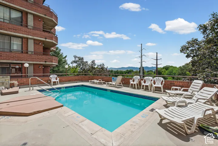Outdoor swimming pool with integrated hot tub, surrounded by a concrete deck with a brick half-wall