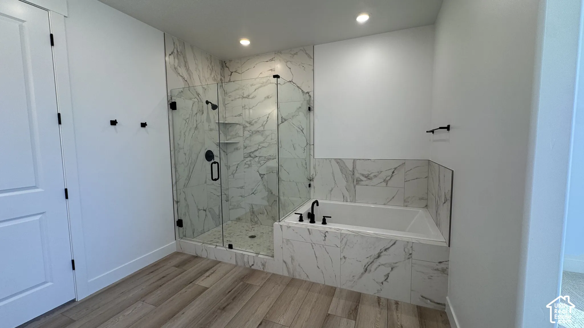Wood-finish flooring leading to a walk-in shower with clear glass enclosure