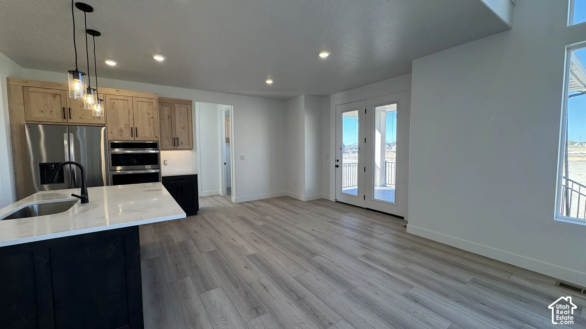 Gourmet kitchen with stainless steel appliances, dual ovens, and a center island with a sink