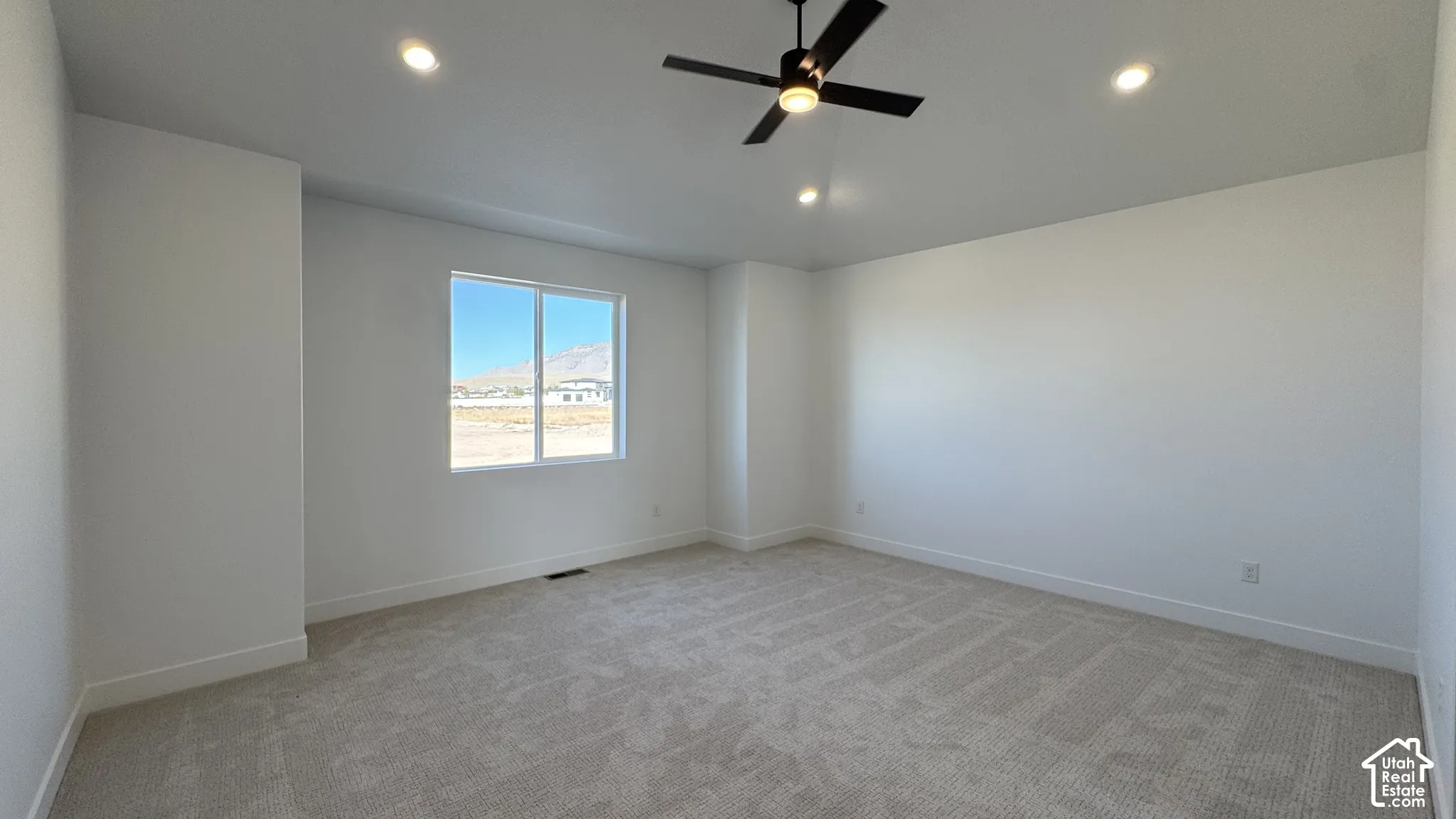 Recessed lighting, ceiling fan with integrated light, large window, and light-toned carpeting