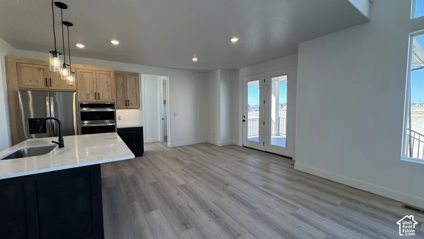 Gourmet kitchen with stainless steel appliances, dual ovens, and a center island with a sink