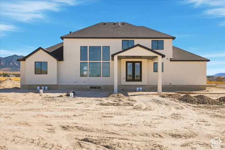 Two-story residence featuring a covered patio, multiple large windows, and a dark shingle roof