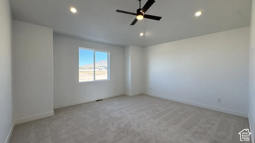 Recessed lighting, ceiling fan with integrated light, large window, and light-toned carpeting