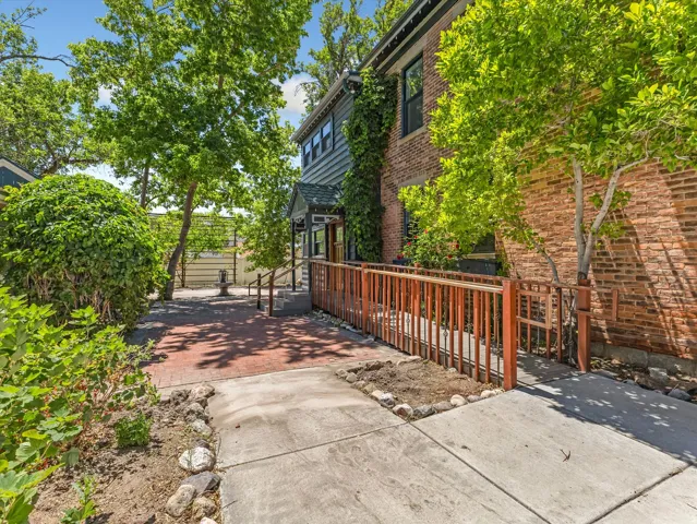 Brick and clapboard exterior featuring a covered entry, established landscaping, a paved walkway, and a ramp access point
