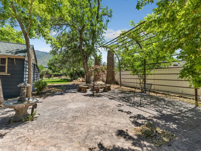 Stamped concrete patio featuring an open trellis, a decorative fountain, and mature trees