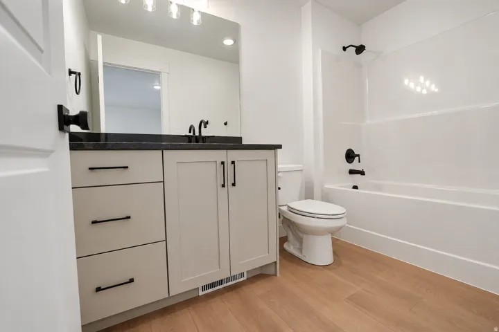 Bathroom featuring a vanity with dark countertop, light cabinetry, and black hardware