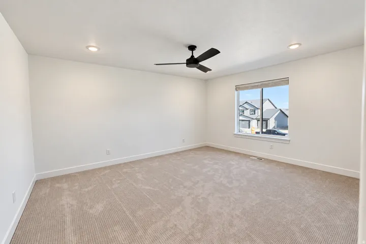 Recessed lighting, ceiling fan, expansive window, neutral wall paint, and beige patterned carpeting