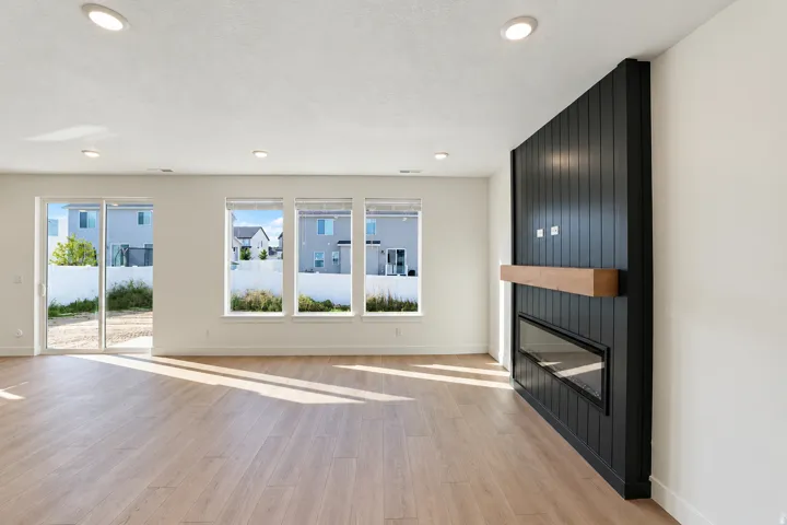 Wide plank wood-finish flooring, recessed lighting, and a linear fireplace with a wood mantle