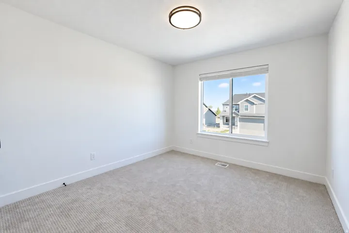Neutral wall color, carpeted flooring, large window, and flush-mount ceiling light