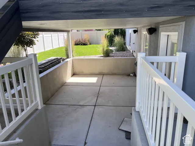 Covered patio area with concrete flooring, accented by a white railing