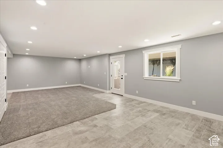 Spacious room featuring recessed lighting, a direct exterior access door, and a large window with white trim
