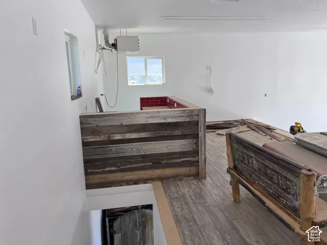 Shop garage - Upper-level loft space featuring a wood-finish flooring, white walls, and a multi-toned wood plank half-wall
