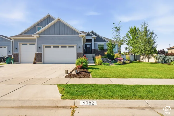 Property exterior featuring light blue siding, stone veneer accents, an attached two-car garage, and a landscaped front yard with a concrete driveway