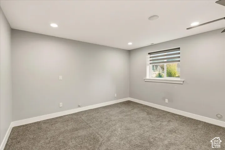 Neutral-toned room featuring light gray walls, plush gray carpeting, and white baseboards