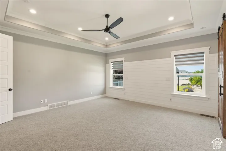 Spacious room featuring a tray ceiling with recessed lighting, a contemporary ceiling fan, and light gray wall paint