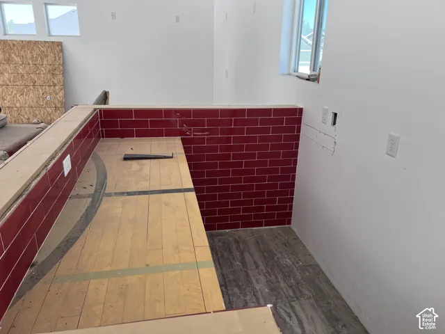 Shop garage - Accent wall featuring red subway tile and an unfinished wood-finish countertop
