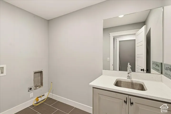Utility room featuring a light gray vanity with a stainless steel sink, a spacious countertop, and a large wall-mounted mirror