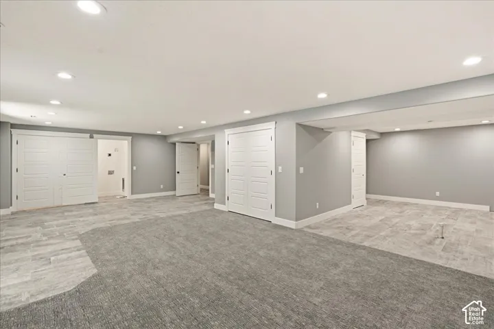Spacious room featuring recessed lighting, a combination of tile and carpet flooring, and multiple white panel doors