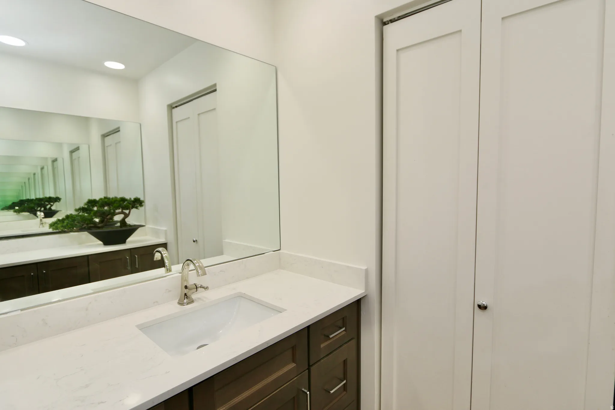 Primary bathroom vanity featuring a quartz countertops, rectangular undermount sink, and large mirrors