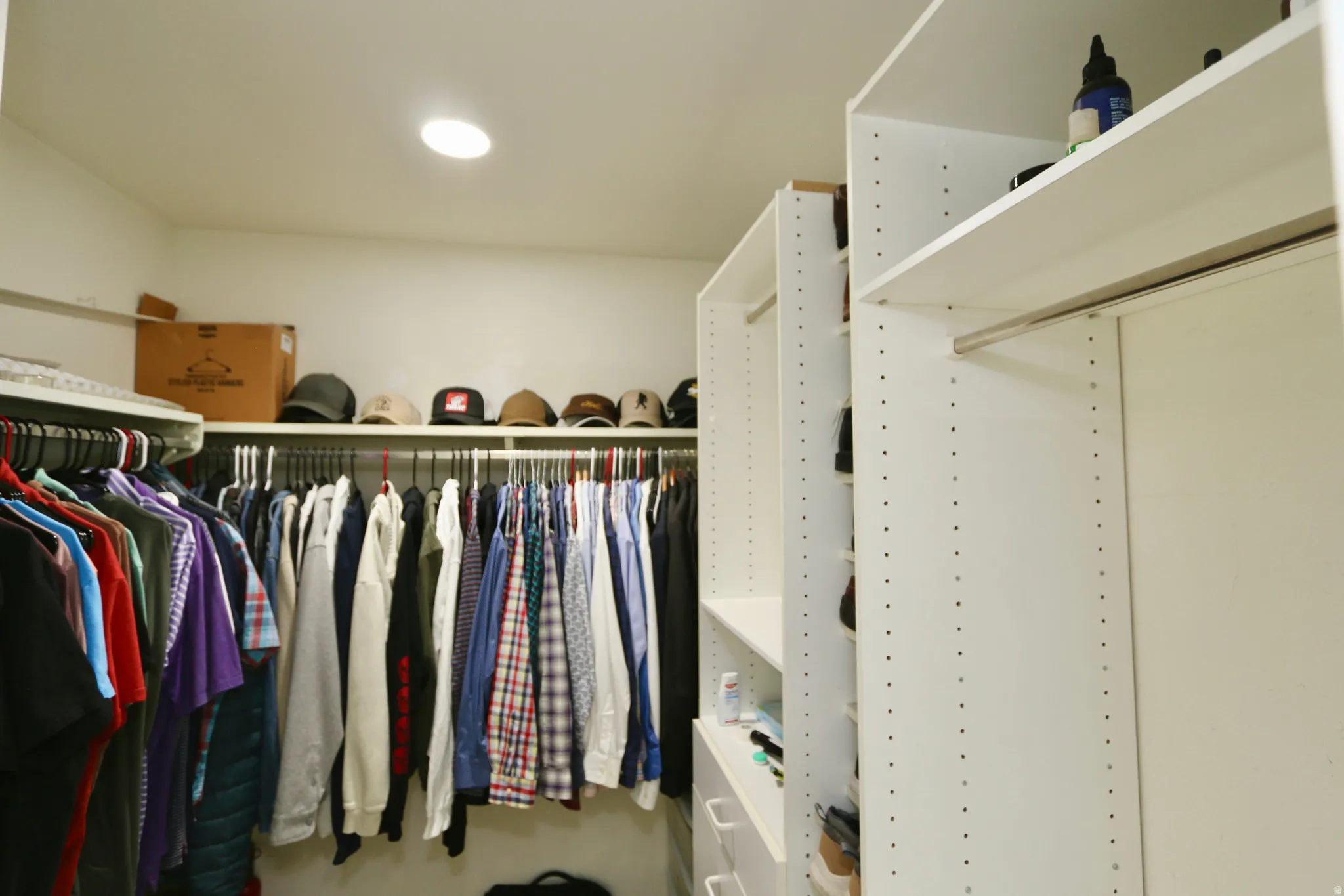 Primary suite walk-in closet featuring recessed lighting, extensive white built-in shelving, and multiple clothing rods