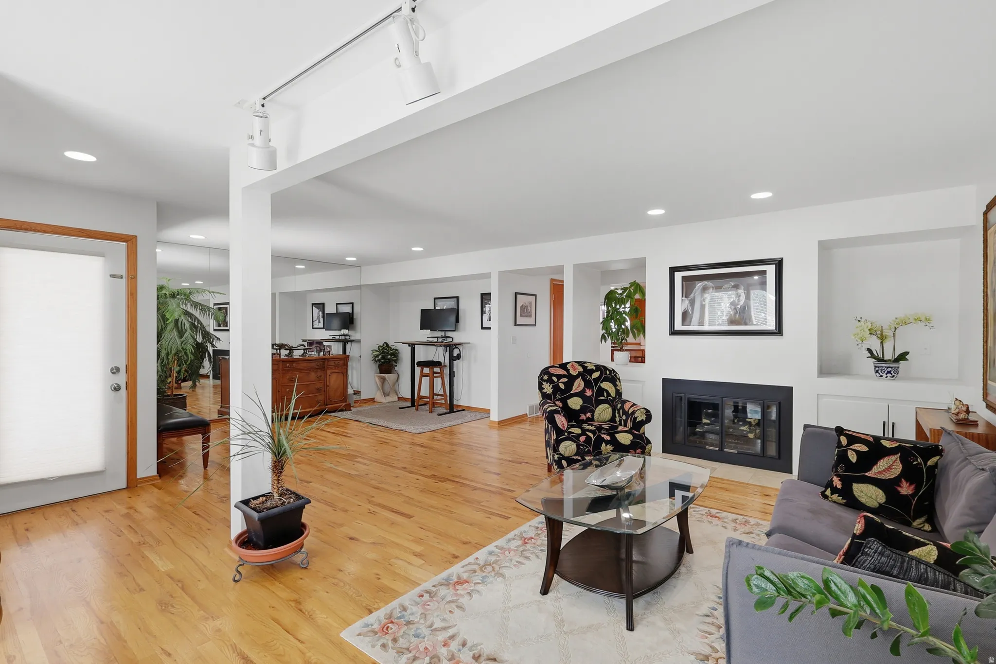 Bright living area featuring wood-finish flooring, recessed lighting, and a fireplace with a black surround